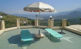 a rooftop patio with two lounge chairs , a large umbrella , and a view of the city at Irida