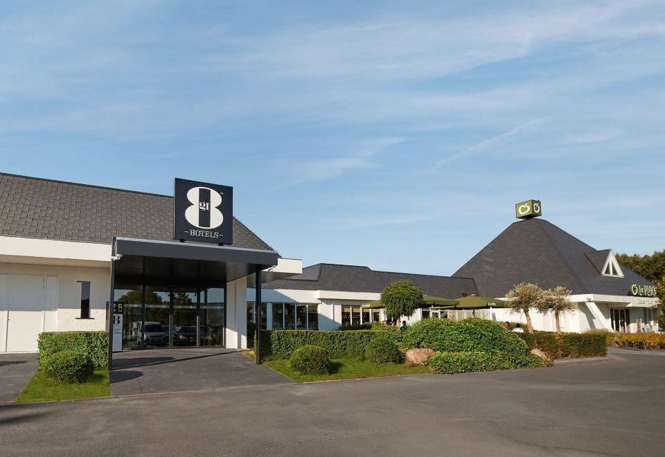 the exterior of a hotel with a black roof and white signage , set against a clear blue sky at Gr8 Hotel Sevenum