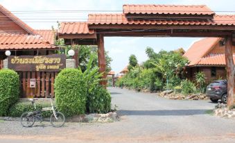 a large wooden gate with a sign above it , leading to a parking lot filled with cars at Ramiarndao Boutique Place Hotel