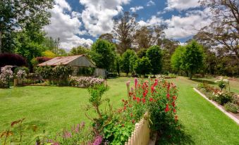 a lush green lawn with a variety of flowers and bushes , creating a picturesque scene at Berrima Bakehouse Motel