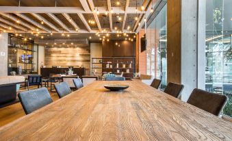 a large wooden table with black chairs in a room with wooden beams and modern lighting at Four Points by Sheraton Puebla