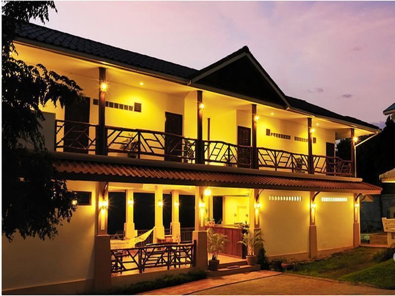 a large building with a balcony and multiple rooms is lit up at night , accompanied by outdoor seating areas at Samprasob Resort
