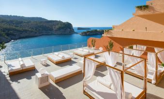 a rooftop terrace with white lounge chairs , umbrellas , and a view of the ocean , set against a clear blue sky at Hotel Galeón