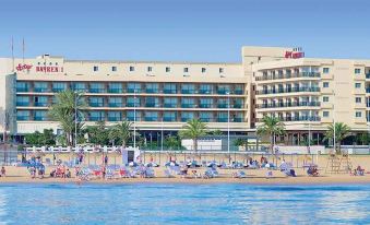 a large hotel with multiple floors and balconies , surrounded by people enjoying the sunny day by the beach at RH Bayren Hotel & Spa