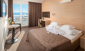 a hotel room with a large bed , a desk , and a window overlooking the ocean at Hotel Olympia