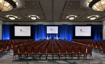 a large conference room with rows of red chairs and blue drapes , set up for an event at Bethesda North Marriott Hotel & Conference Center
