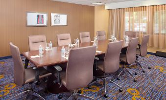 a conference room with a large wooden table surrounded by chairs , water bottles , and framed pictures on the wall at Courtyard Montvale