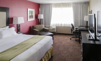 a hotel room with a bed , desk , chair , and window is shown in this image at Holiday Inn Express Big Rapids