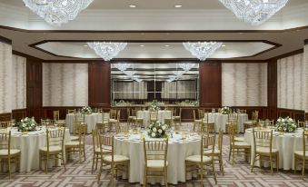 a large banquet hall with multiple tables set for a formal event , featuring gold chairs and white tablecloths at Amman Marriott Hotel