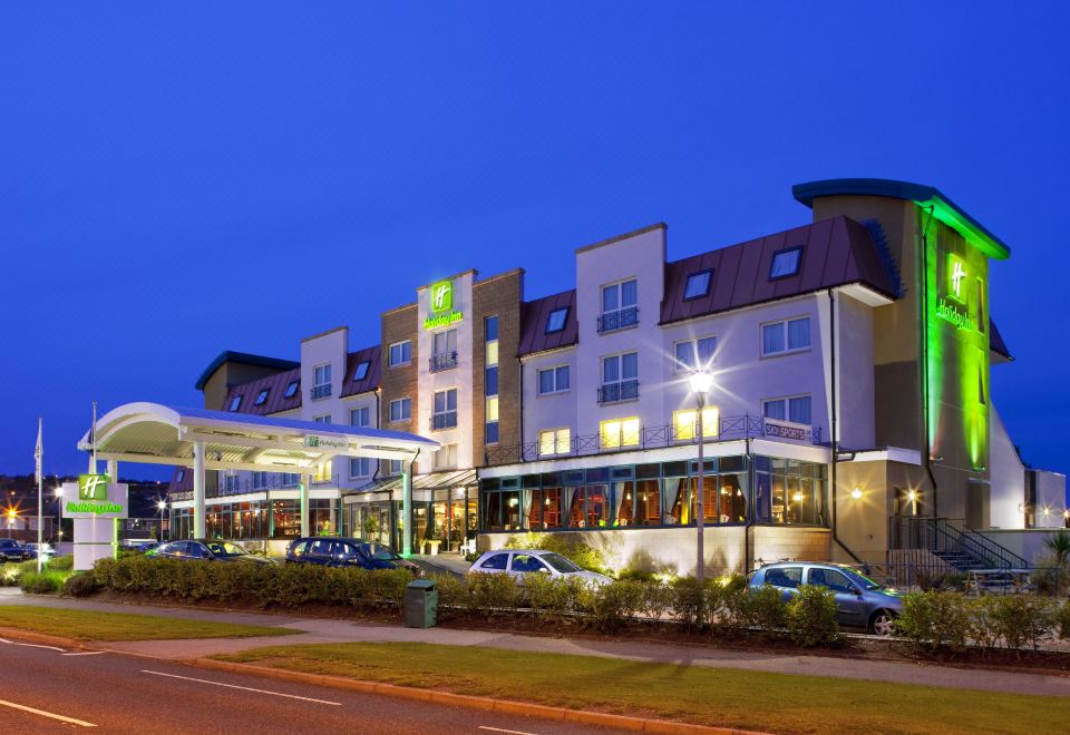 an exterior view of a hotel or motel at night , with a large parking lot in front at Holiday Inn Aberdeen - West