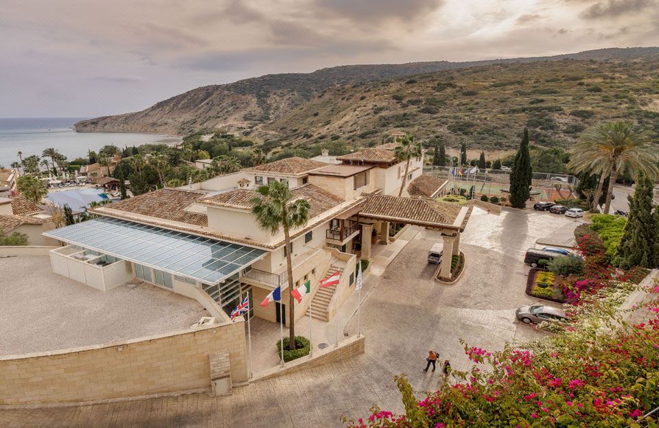 a large house with a pool and palm trees is surrounded by mountains , and a car parked in front of it at Columbia Beach Resort