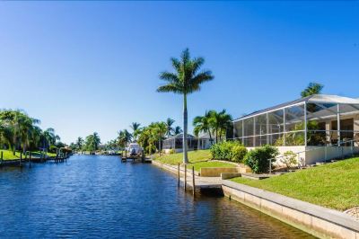 a body of water surrounded by palm trees , with a house in the background on a sunny day at Italy