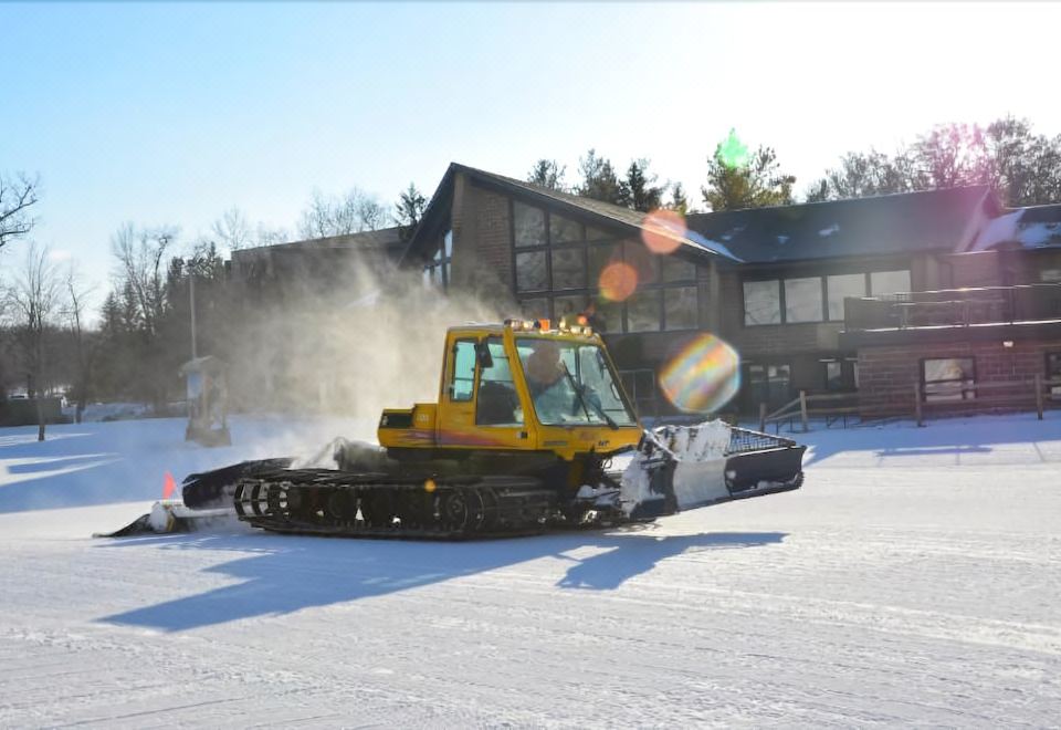 a yellow snowplow is pulling a large amount of snow in front of a house at Devil's Head Resort