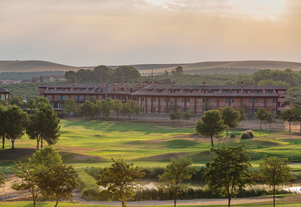 a large building surrounded by a lush green golf course , creating a picturesque setting for a golf course at Exe Layos Golf