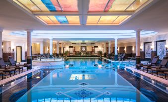 an indoor swimming pool with a glass ceiling , allowing natural light to illuminate the space at Althoff Seehotel Überfahrt