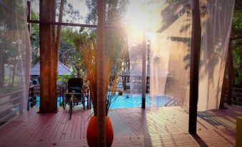 a large wooden deck overlooking a pool and surrounding area , with a potted plant in the foreground at Baanrai Riverkkwai Resort