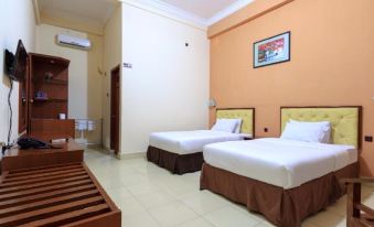 a hotel room with two beds , a tv , and an air conditioner , all neatly arranged in an orange - walled room at Hotel Elvin