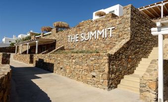 "a large stone building with the word "" the summit "" written on it , surrounded by grass and trees" at The Summit of Mykonos