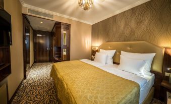 a large bed with a gold blanket is in a room with a chandelier and patterned carpet at Kings Casino & Hotel