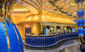 a luxurious hotel lobby with a blue and gold themed reception desk , gold ceiling lights , and marble flooring at Kings Casino & Hotel