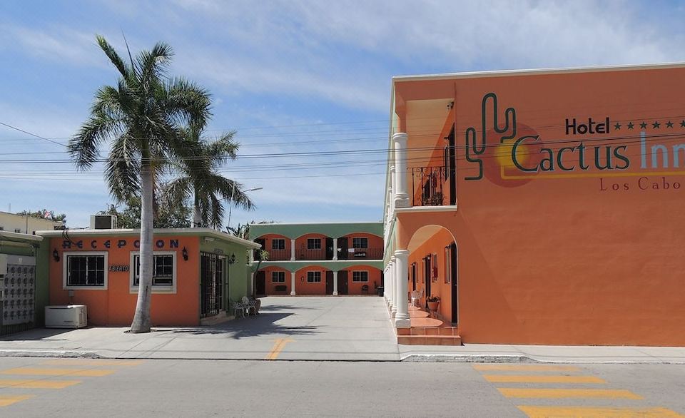 "a city street with a row of orange buildings , one of which has the word "" cafe "" painted on it" at Cactus Inn Los Cabos