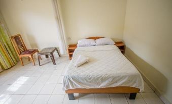a bed with a white comforter and pillows is in a room with two nightstands at Collin Hotel