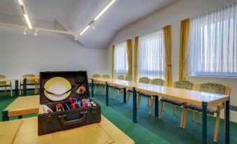 a conference room with green carpeted floors , yellow chairs , and a wooden desk with a handbag on it at Hotel Astor