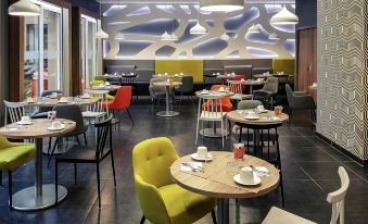 a modern restaurant with various dining tables and chairs arranged in a comfortable seating area at Mercure Libourne Saint Emilion