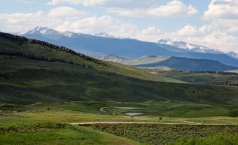 a scenic view of a green valley with mountains in the background and clouds in the sky at The Inn at Silvercreek