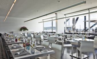 a modern restaurant with white tables and chairs , wine glasses , and bottles on the tables at Altis Belem Hotel & Spa, a Member of Design Hotels