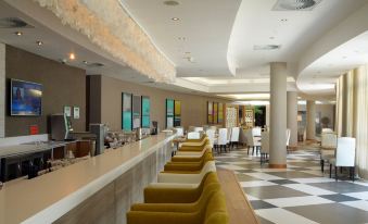 a modern , well - lit hotel lobby with various seating options and a check - in desk , including green chairs and tables at Holiday Inn Mauritius Mon Tresor