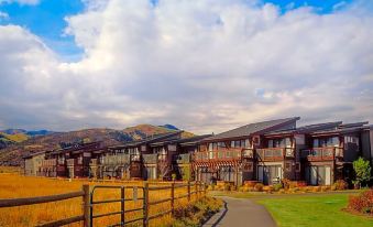 a row of wooden houses surrounded by a grassy field and a wooden fence , with mountains in the background at Newpark Resort