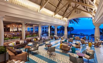 a modern hotel lobby with wooden furniture , a blue - tiled floor , and a view of the ocean at Curacao Marriott Beach Resort