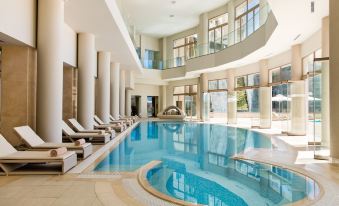 an indoor swimming pool surrounded by lounge chairs , where people are relaxing and enjoying their time at Ikos Oceania