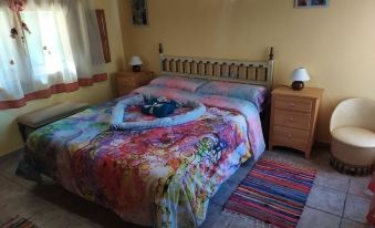 a well - decorated bedroom with a large bed , two nightstands , and a colorful bedspread , all set against a yellow wall at La Esencia