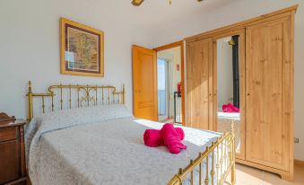 a bedroom with a bed , wooden cabinets , and a pink teddy bear on the bed at Golf
