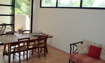 a dining room with a wooden dining table , chairs , and a couch situated in front of a large window at Holiday Home Villa Isabelle