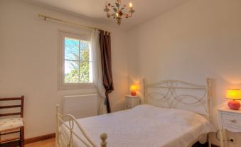 a white bedroom with a large bed , a lamp on the nightstand , and a window at La Fabrique