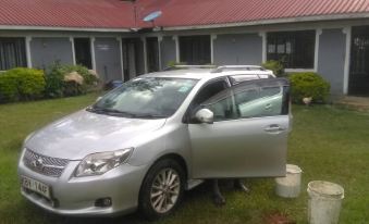 a silver car is parked in a grassy area near a house , with buckets on the lawn nearby at Eddys Resort