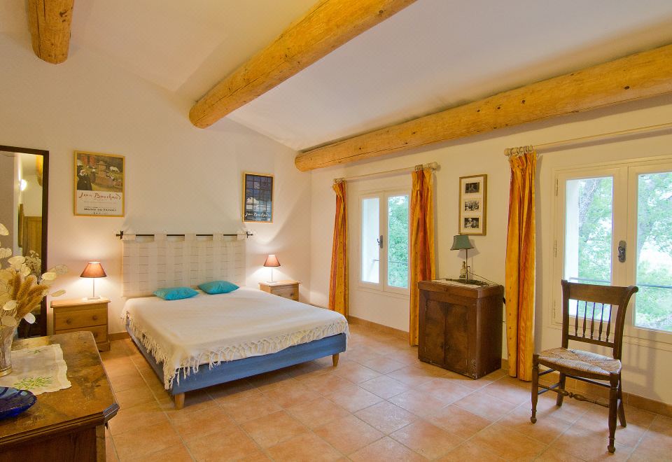 a spacious bedroom with a large bed , wooden beams on the ceiling , and a dresser nearby at Les Cotes