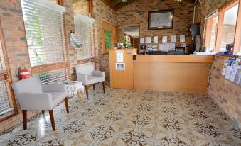 a room with a wooden counter , two white chairs , and a brick wall with a window at Sandhurst Motor Inn Bendigo