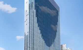 A tall building with glass windows is surrounded by other buildings on both sides at iclub Mong Kok Hotel