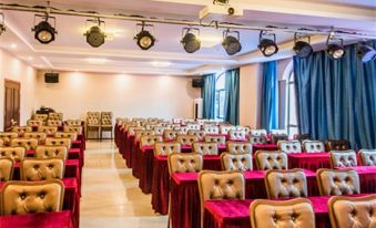 There is a large event space with rows of red chairs and a projector screen at the front at Kela Hotel