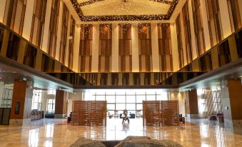 a large , ornate room with a high ceiling and wooden paneling features two seats in front of a sculpture at Pullman Changbaishan Resort