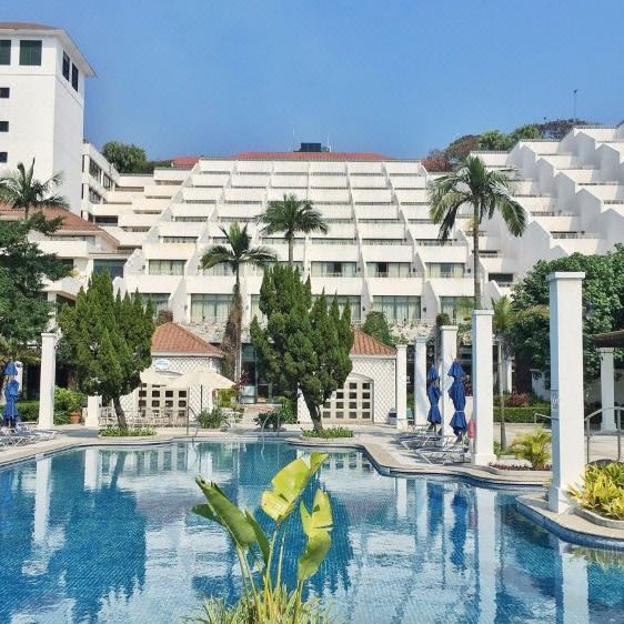 There is a large building with a pool and apartments in the background at an upscale resort or hotel at Grand Coloane Resort Macau