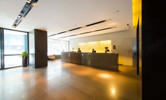 The lobby features large windows and ceiling lighting, accompanied by an office space equipped with a desk, computer, and a seating area comprising comfortable chairs and a coffee table at Empire Hotel Hong Kong - Causeway Bay