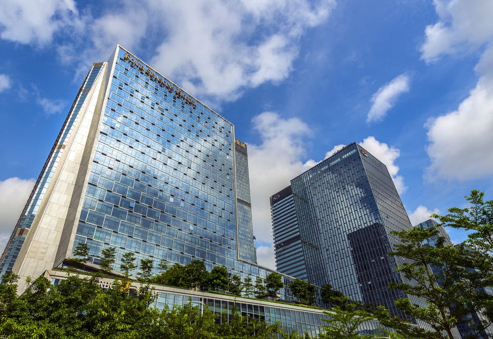 The city's skyline, adorned with towering skyscrapers and a prominent tree in the foreground, is a sight that captivates many at Four Seasons Hotel Shenzhen