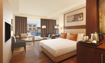 a large bed with white linens is in a room with wooden floors and brown walls at DoubleTree by Hilton Agra