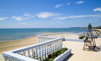 a balcony overlooking the beach , with a white railing and blue sky in the background at Sanctuary Resort