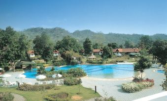 a large , well - maintained resort with a pool surrounded by trees and mountains in the background at Supalai Pasak Resort Hotel and Spa